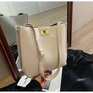 Close-up of beige lychee pattern bucket bag with gold twist lock and dual straps