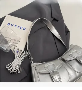 Close-up of silver metallic faux leather shoulder bag with vintage buckle and woven strap