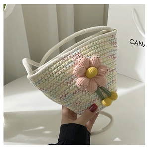 Close-up of woven bucket bag featuring colorful stitching and a large pink fabric flower