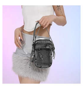 Detail view of mini washed denim crossbody bag with drawstring decoration and zipper top