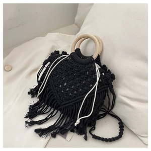 Detail of bohemian black macrame bag featuring long tassels and round wooden handles