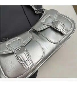 Detail of silver Y2K shoulder bag featuring metallic textured PU and dual buckle pockets