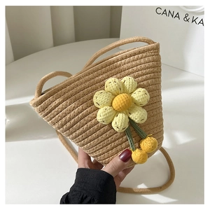 Detail of straw bucket bag with sunflower decoration and cherry charms in hand