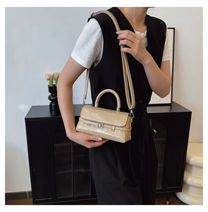 Beige glossy mini crossbody bag styled by model in a minimalist home interior setting