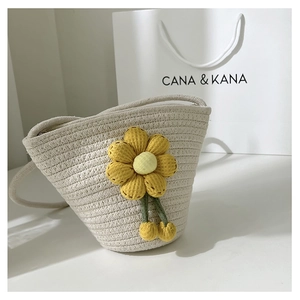 Detail of a mini beige woven bucket bag featuring a cute yellow sunflower and green stems