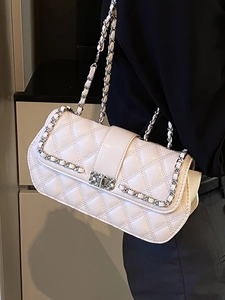 Elegant white quilted crossbody bag with a silver chain strap worn by a female model