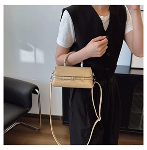 Detail of elegant beige crossbody bag with top handle and flap closure shown by model