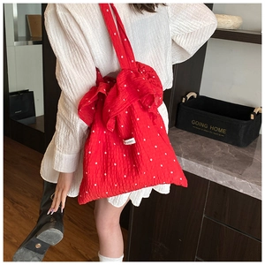 Detail of red floral tote bag with oversized bow and ruffled bubble fabric texture