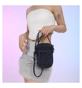 Mini washed denim crossbody bag featuring a front pocket and knotted detail on model