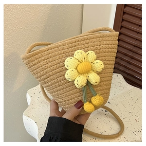 Detail of hand-woven bucket bag with yellow 3D floral decoration and knit pom-poms