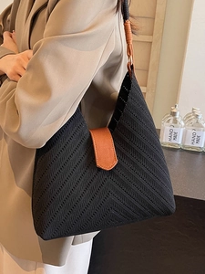 Minimalist black woven tote bag featuring unique V-shaped ripples and brown leather strap