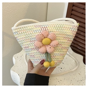 Close-up of a cream woven bucket bag with pink fabric flowers and colorful wave stitching