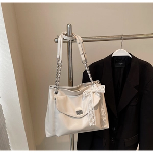 Detail der cremefarbenen PU-Ledertasche mit Metalldrehverschluss und Spitzen-Schleife