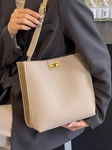 Elegant beige lychee grain bucket bag with gold lock and adjustable shoulder strap