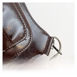 Gros plan sur la texture en cuir marron foncé avec boucle métallique et coutures précises
