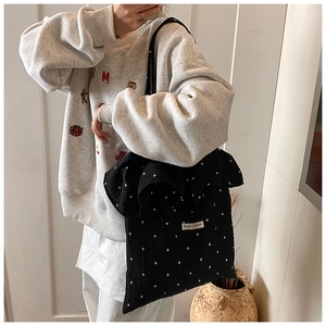 Detail of black floral ruffle shoulder bag with Magic Pocket tag on crinkled fabric
