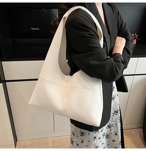 Close-up of a white soft leather hobo bag showing the pebbled texture and stitched seam details
