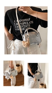 Detail view of silver metallic pillow bag with plush bear charm and silk scarf handle