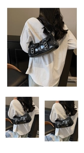 Detail view of black glossy PU leather underarm bag with silver buckles and moto-style pockets