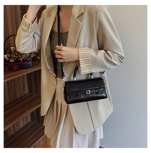 Detail view of high-gloss black square handbag with metal buckle and fixed handle strap