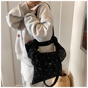 Detail of black floral tote bag with ruffle edges and white flower pattern shown on shoulder