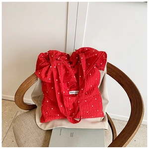 Detail shot of red seersucker tote bag with floral print and Magic Pocket label on rattan chair