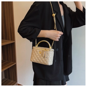 Crossbody view of quilted mini vanity bag with gold ball chain and metal handle