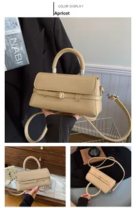 Detail view of the apricot square handbag with curved handle and silver hardware accents