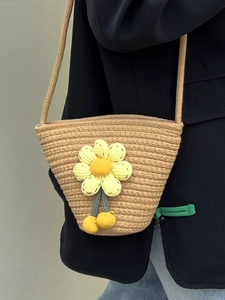 Beige hand-woven bucket crossbody bag with a 3D crochet flower and yellow pompoms