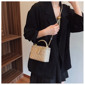 Detail view of a quilted beige leather mini vanity bag with a gold metal handle