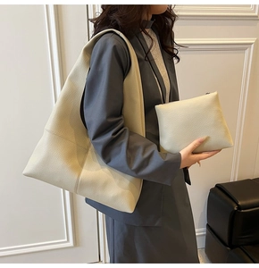 Detail view of large cream leather tote bag and matching pouch on a model's shoulder