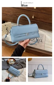 Detail view of light blue matte leather handbag with decorative strap and metal hardware