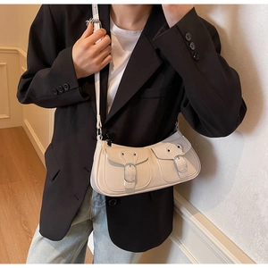Detail view of cream vintage baguette bag with silver buckles and adjustable shoulder strap