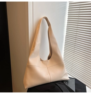 Detail of minimalist beige faux leather hobo bag showing refined litchi grain texture