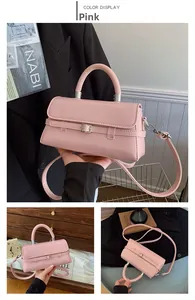 Pink minimalist crossbody bag featuring silver buckle detail and leather handle shown in use