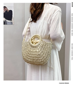 Straw woven basket bag with drawstring liner and crossbody strap shown on a model