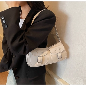 Detail of cream underarm bag featuring front double pockets and silver metal buckle