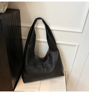 Detail shot of black pebbled leather tote bag with cross stitching on vintage book