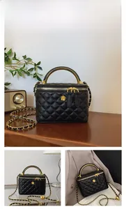 Detail of black quilted bucket bag featuring gold camellia hardware and chain strap
