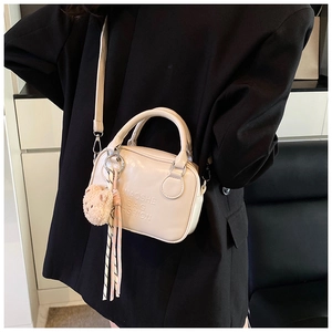 Detail of cream mini pillow bag featuring embossed logo and cute bear charm pendant