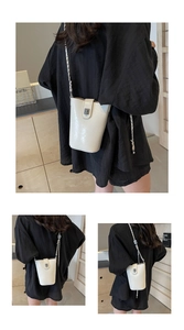 Detail of cream white bucket bag with glossy leather texture and silver chain strap