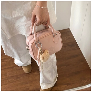 Pink patent leather pillow bag with top handles and a plush bear pendant detail