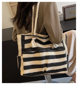 Detail of hand-woven striped tote bag featuring thick cotton rope handles and tassels