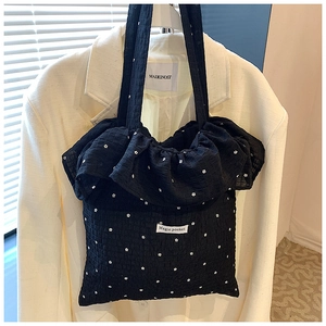 Close-up of black floral tote bag with ruffled edges and white Magic pocket label