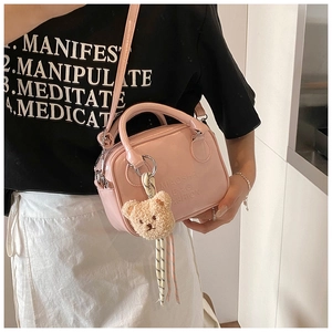 Pink patent leather pillow bag with engraved logo and cute plush bear charm detail