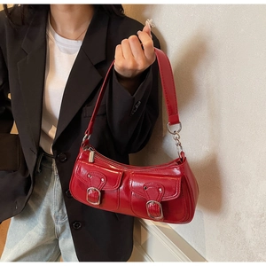 Detail of red patent leather shoulder bag with functional dual buckled pockets