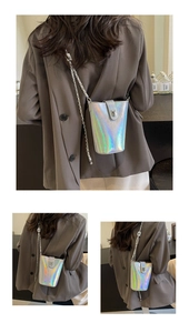 Detail view of holographic silver bucket bag showing rotating lock and metal chain strap