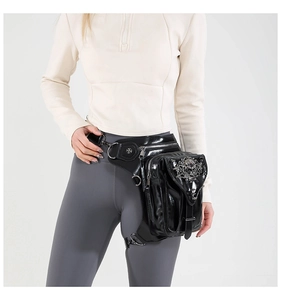 Detail of punk style leg bag with silver skull buckle and glossy black finish