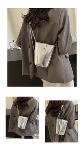Detail of silver metallic bucket bag with magnetic flap and fine chain strap