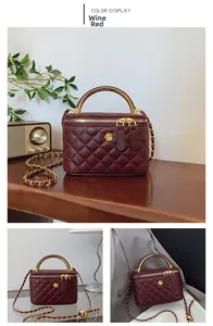 Detail of wine red quilted bucket bag with gold handle, metal chain and floral accent